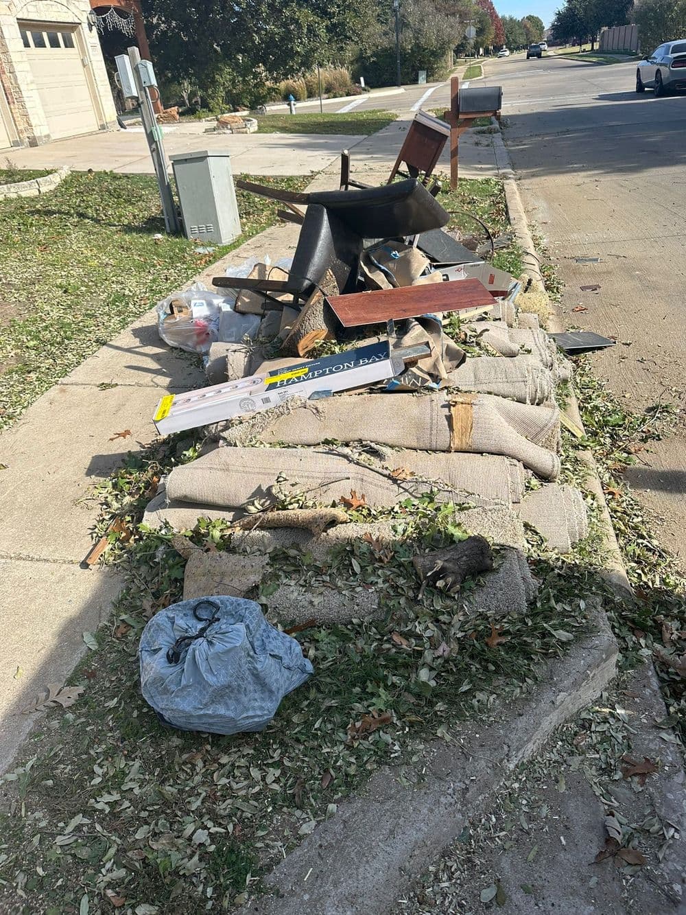 Discarded furniture and debris on a curbside, including chairs, wood, and trash bags.