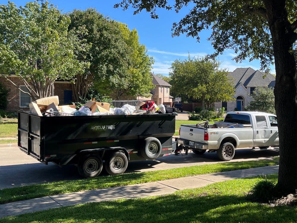 Dump truck filled with junk parked on a residential street in sunny suburb.