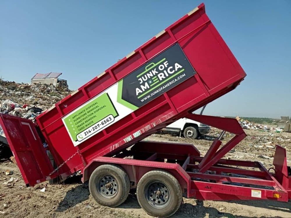 Red dumpster from Junk of America at a landfill site, promoting junk removal services.